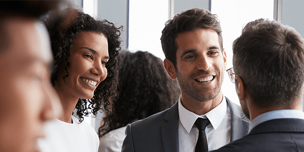 A group of two men and one woman smiling and chatting.