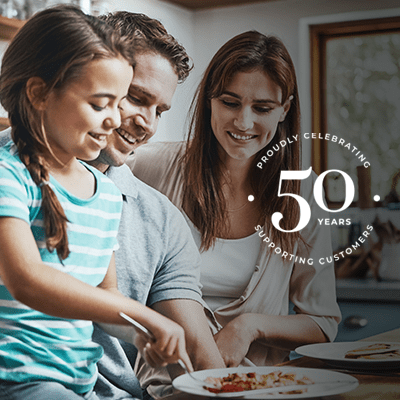 A family of three smiling whilst having breakfast.