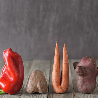 imperfect vegetables lined up in a row on a wooden table