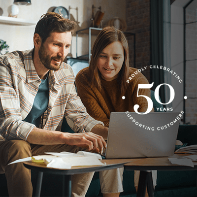 A mid shot of a man and a woman sat together reading a laptop.