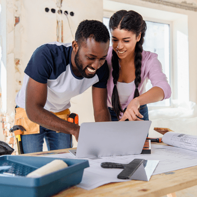 Young couple looking at laptop screen whilst renovating house - l