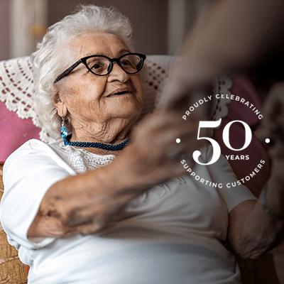 A mid shot of someone helping an elderly woman get up.