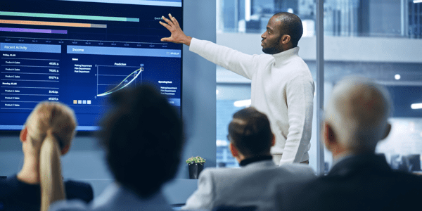 Man presenting on a screen to a room of people.