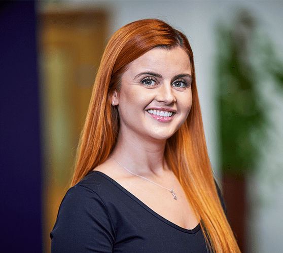 A woman with long ginger hair smiling wearing a black top.