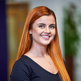 A woman with long ginger hair smiling wearing a black top.