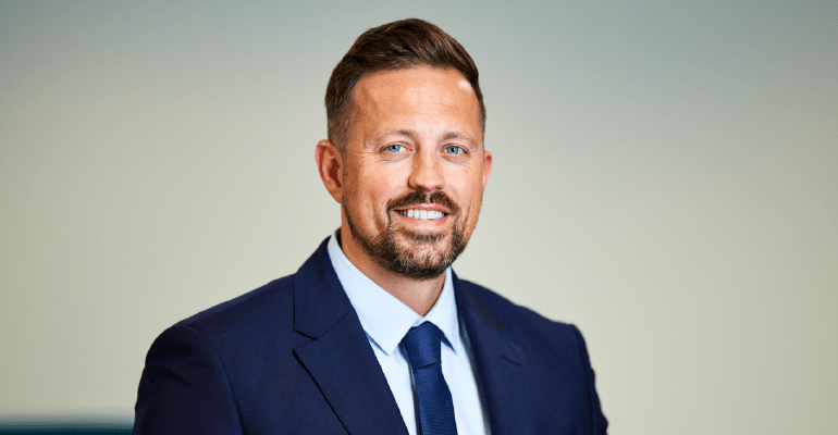 Man smiling wearing a navy blue suit L