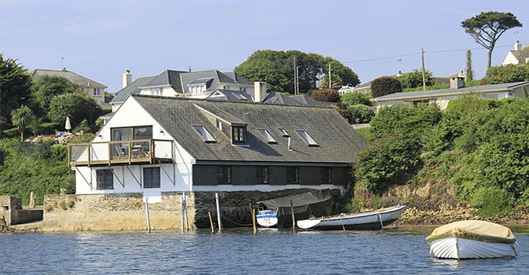 A building that hovers above the water with trees around it.