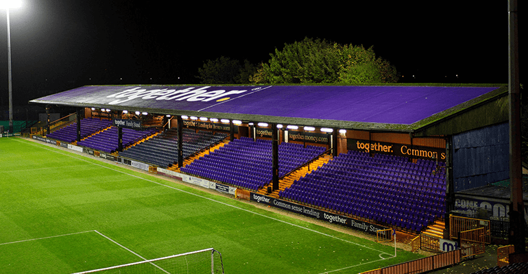 A football field with a purple seating area on the right-hand side.