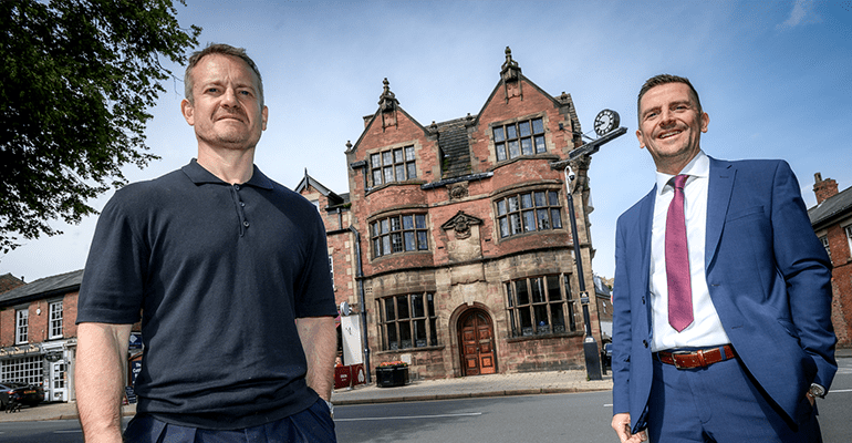 Ashley Landson and Ritchie Watson stood smiling outside old bank.