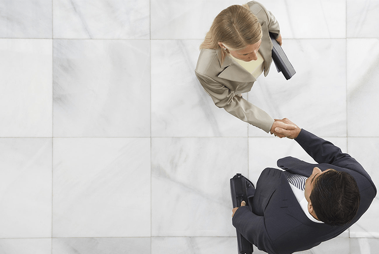 Business man and woman shaking hands viewed from above