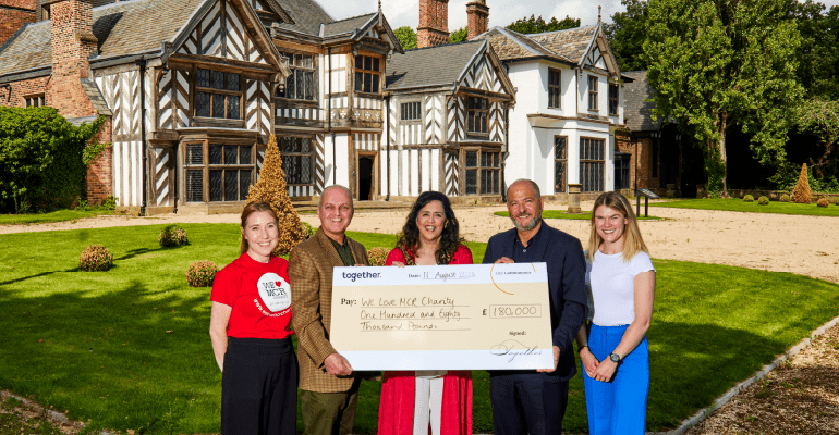 Four people outside smiling holding a cheque