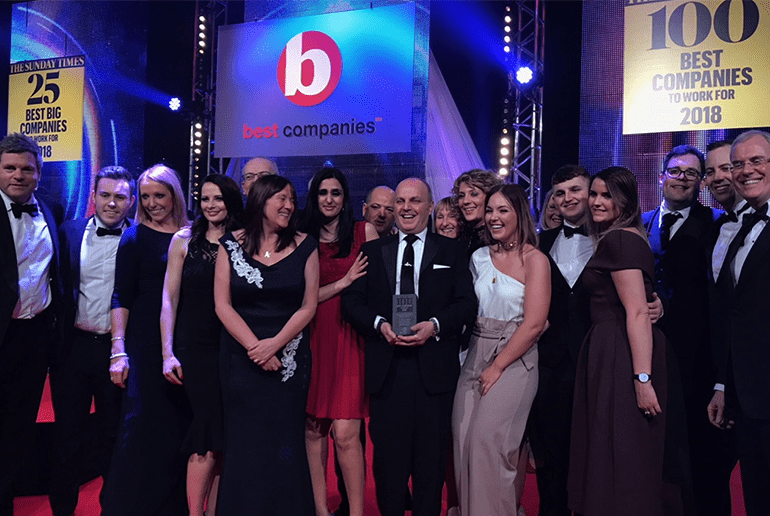 group of people at an awards ceremony in black tie attire holding an award