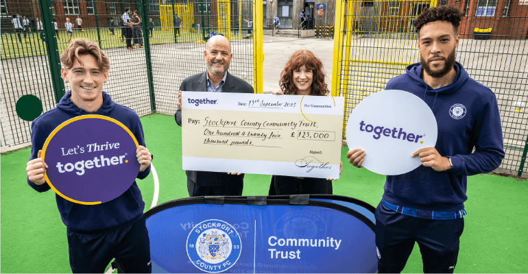 Group of people smiling holding a cheque.