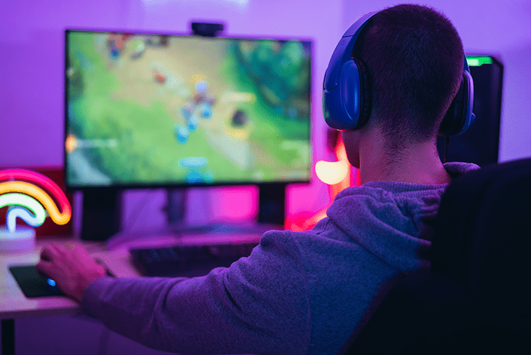 man sat on a chair playing a computer game with headphones on 