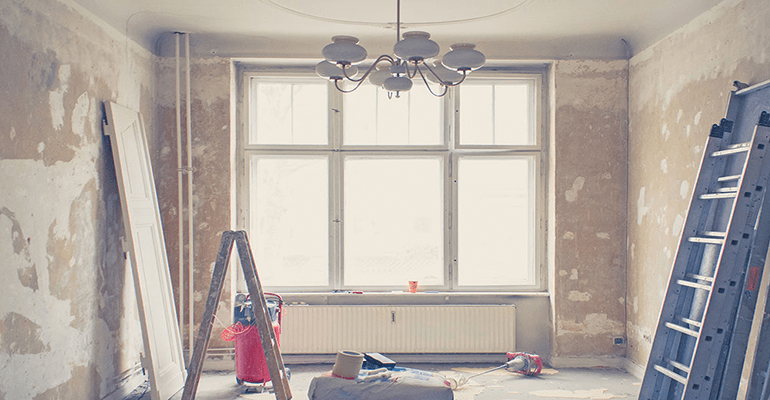 room being renovated with ladders leaning against the wall and decorating equipment around the room