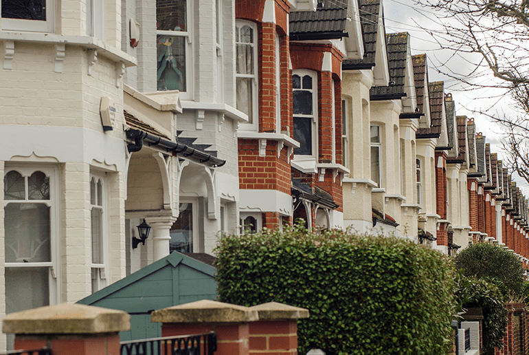 row of houses on a street with bushes at the front