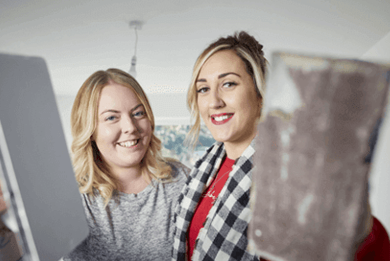 two girls smiling holding trowels 