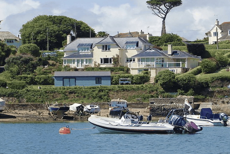 white house overlooking a lake with boats on