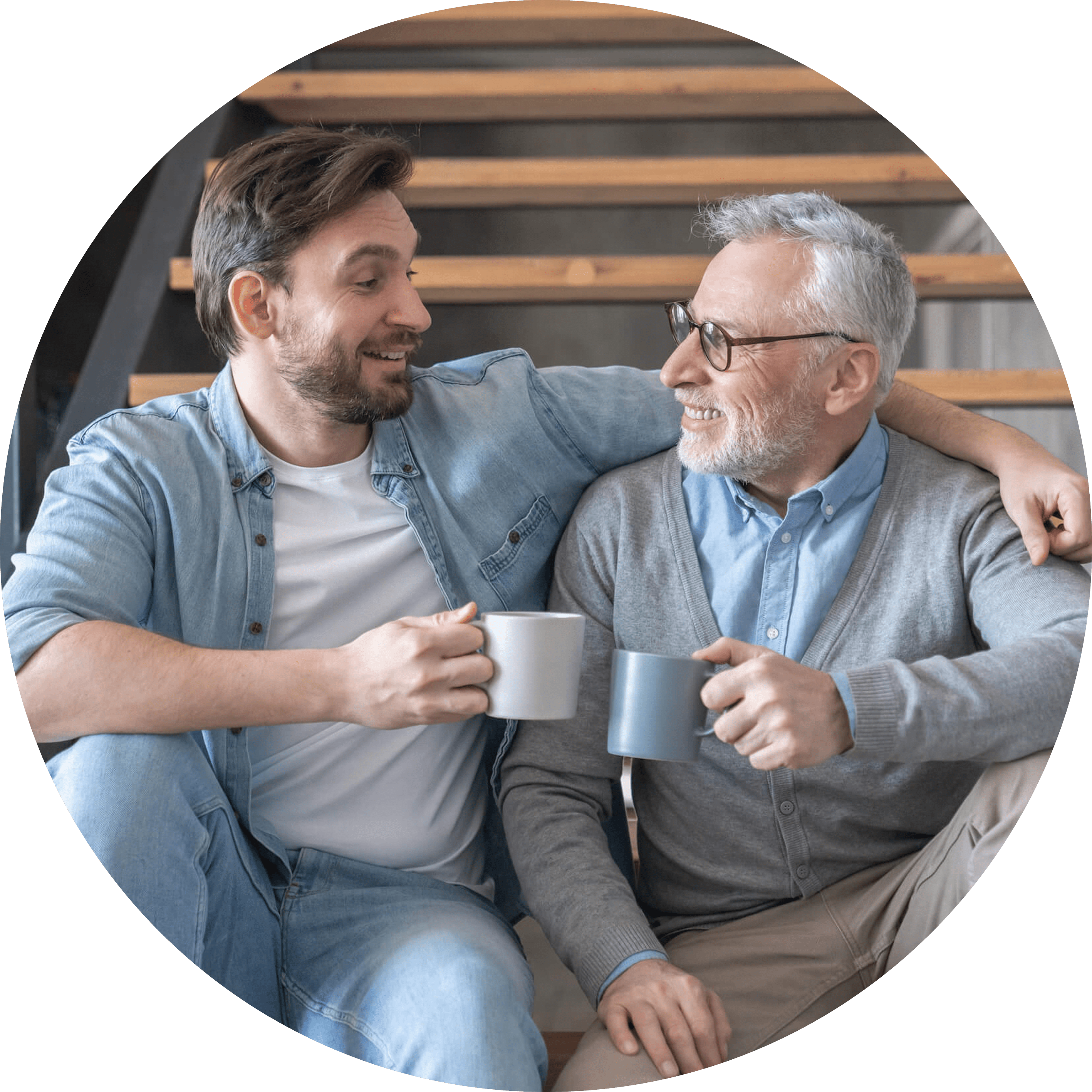 A close up of two men, one old and one young, sitting together talking whilst sat on a staircase.