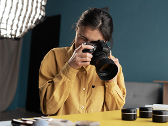 A woman with dark hair taking close up pictures on a desk.