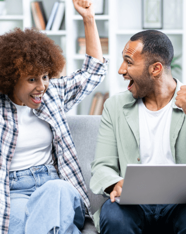 Couple cheering while looking at a laptop