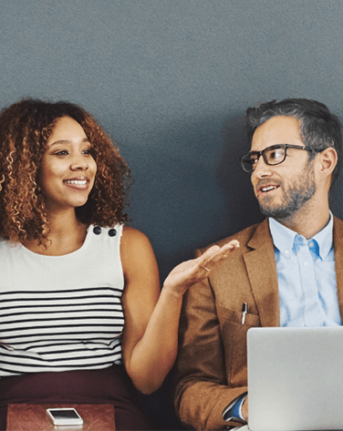 A man and woman sat next to each other chatting.