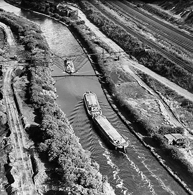 A black and white birds eye view of boats passing each other in a canal.