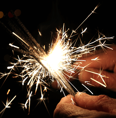 A close up of a hand lighting a sparkler.