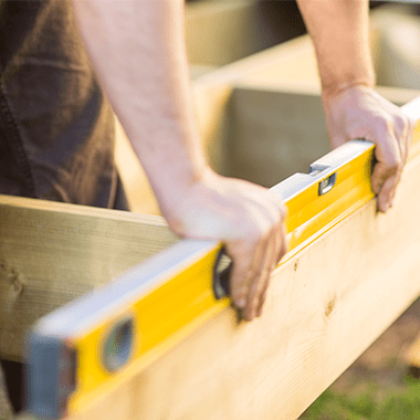 builder holding a spirit level on a wooden frame 