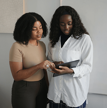 two young women looking at tablet device - l