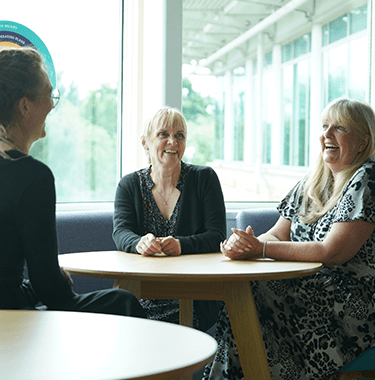 A group of three colleagues laughing around a table.