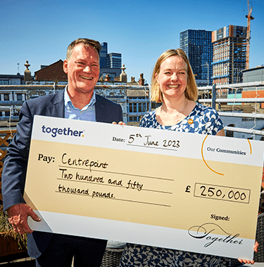 Two people holding a large cheque for centrepoint.