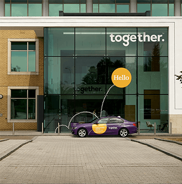 A long shot of Togethers building with the purple brand car outside.