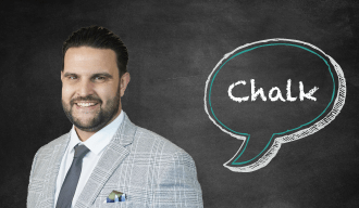 Blackboard with speech bubble saying Chalk on the right and a dark haired man in a grey suit